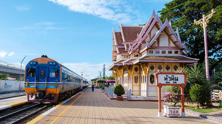 Hua Hin train station in Thailand with passengers waiting, featuring a train at the station against a clear blue sky on 10 September 2022, symbolizing travel and daily life in Thailand.