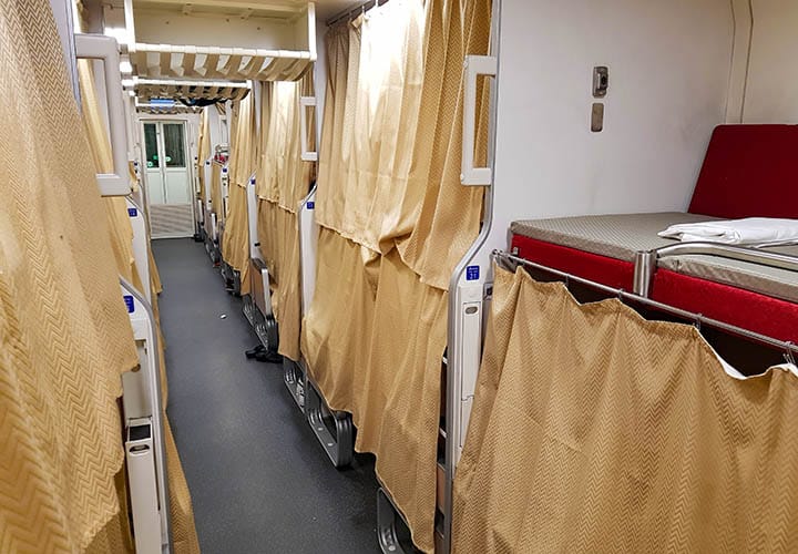 Interior view of the night train to Udon Thani with individual beds separated by curtains, departing from Krungthep Aphiwat Central Terminal in Bangkok, showcasing a cost-effective travel option in Thailand.